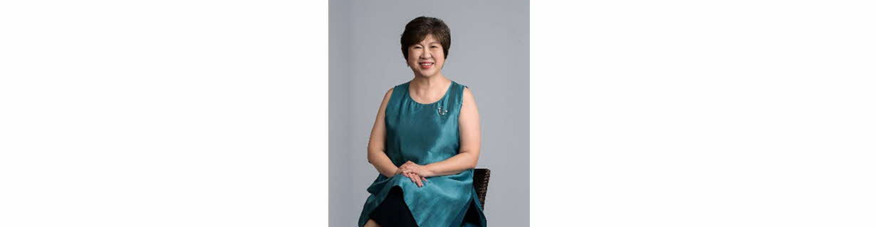 Portrait of Janet Ang, woman in a sleeveless dress and short hair, smiling